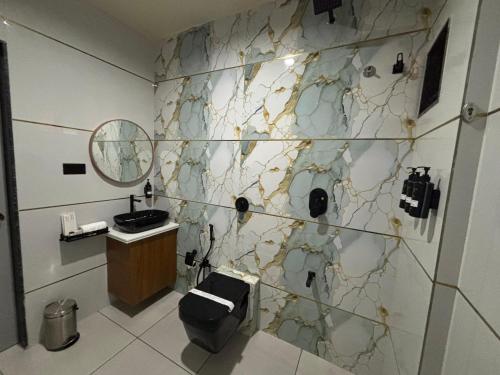 a bathroom with a marble wall with a sink and a mirror at Krushnam Villa Resort Somnath by The Cellton Hotels & Resorts in Somnath