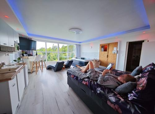 a woman laying on a couch in a living room at Wellness pod zvezdami, Maribor - PRIVATE in Maribor