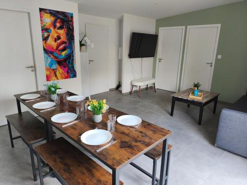 a dining room with a table and a painting on the wall at Gîtes Néphélie votre cocon tout confort aux portes du Puy duFou - Climatisé, Terrasse, Parking in Les Épesses