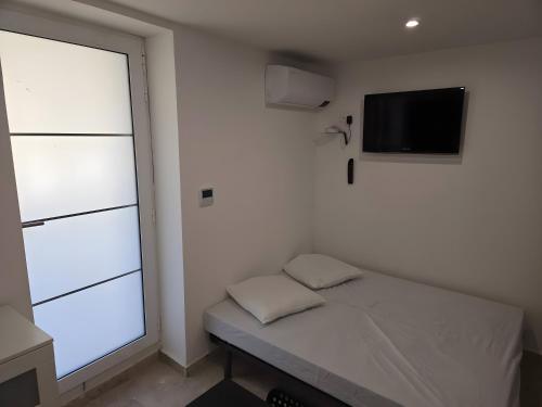 a small bedroom with a bed and a television at Canto Cigalo Rdc 2 in Robion en Luberon