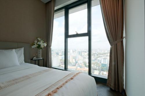 a bedroom with a white bed and a large window at Lancaster Legacy Executive Apartments in Ho Chi Minh City