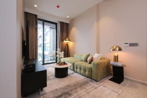 a living room with a green couch and a window at Lancaster Legacy Executive Apartments in Ho Chi Minh City