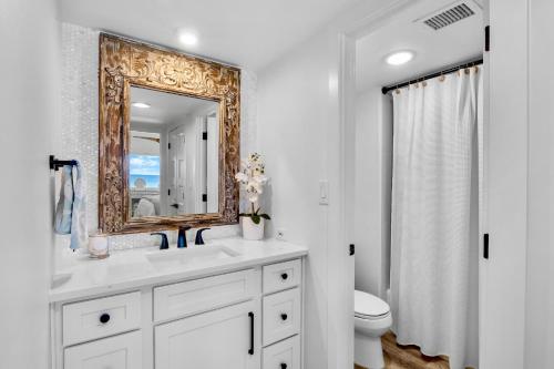 een badkamer met een wastafel en een spiegel en een toilet bij Shimmering Shores in Anna Maria Island