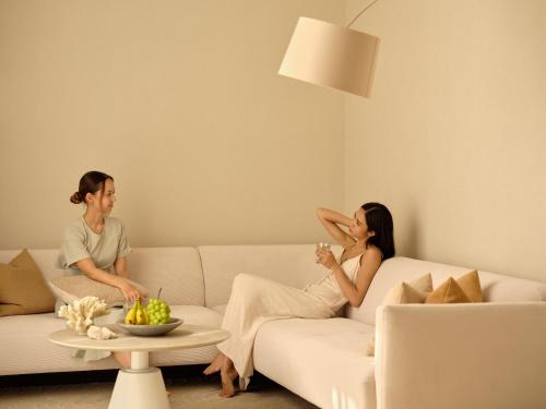 two people sitting on a couch in a living room at URUUMI Onna Pool Villa ｳﾙｳﾐ ｵﾝﾅ ﾌﾟｰﾙ ｳﾞｨﾗ -公式- in Onna