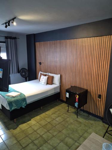 a bedroom with a bed and a wooden wall at Studio Quartzo verde, Centro. in Campos dos Goytacazes