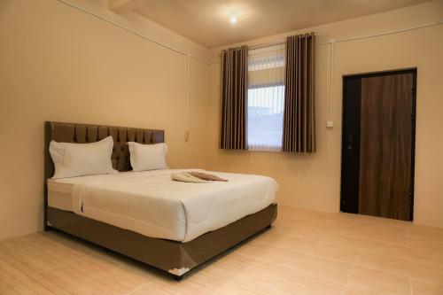 a bedroom with a large bed with white sheets and a window at Mandalika Queen Studio in Kuta Lombok