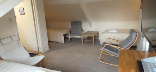 a room with two beds and two chairs and a table at Edward Hotel in Gloucester