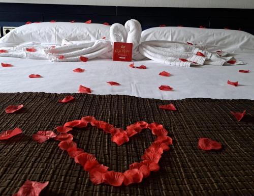 a bed with red rose petals in the shape of a heart at Amura Alcobendas in Alcobendas