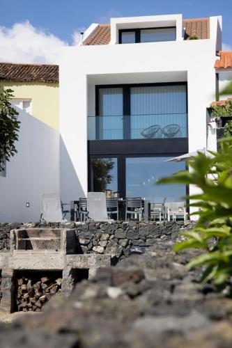 a house with glass windows and chairs on a stone wall at Casa Dona Isabel - ocean suites in Lagoa
