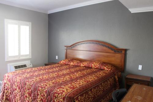 a bedroom with a large bed with a wooden headboard at Town House Motel in Lynwood