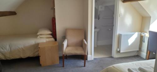 a room with two beds and a chair and a table at Edward Hotel in Gloucester