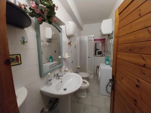 a bathroom with a sink and a toilet and a mirror at Casa Piera con vista mare da 2 a 4 persone in Badesi