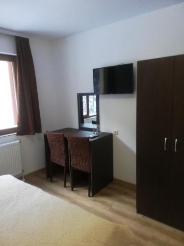 a room with a desk and a table with chairs at семеен хотел Обзор in Progled