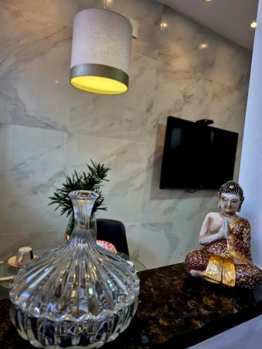 a glass vase sitting on a table with a statue at Apartment with outdoor area, cozy in Campos dos Goytacazes