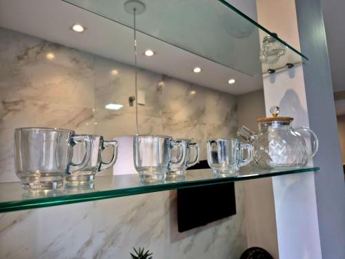 a row of glass pitchers on a glass shelf at Apartment with outdoor area, cozy in Campos dos Goytacazes