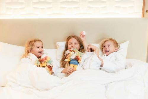 three little girls laying in bed with white sheets at The Ritz-Carlton, Vienna in Vienna