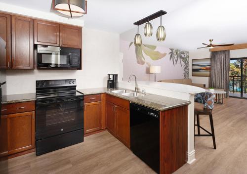 a kitchen with wooden cabinets and a black appliance at Tahiti Village Resort & Spa in Las Vegas