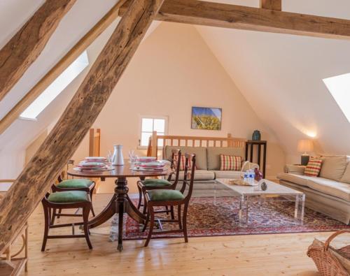 a living room with a table and chairs and a couch at Aux Roses et aux Poutres - Jardin - Arrivée Autonome in Le Tremblay-le-Vicomte