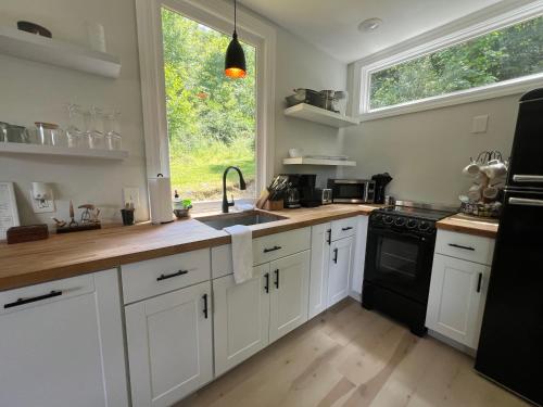 a kitchen with white cabinets and a sink and a window at The Hideaway on Tacketts - Shipping Container in Hurricane