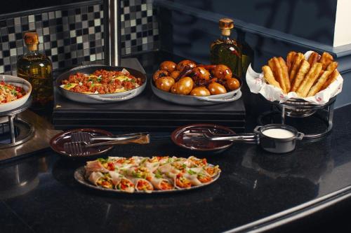 a counter topped with plates of food and bowls of food at Tbilisi Marriott Hotel in Tbilisi City
