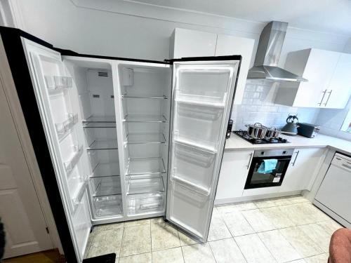 a kitchen with an empty refrigerator in a kitchen at Spacious 4Bedroom - 10mins to London Bridge with Parking & Garden in London
