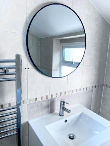 a bathroom with a sink and a mirror at Spacious 4Bedroom - 10mins to London Bridge with Parking & Garden in London
