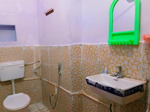 a bathroom with a toilet and a sink and a mirror at Kanchan Lata Homestay in Banāras Cantonment