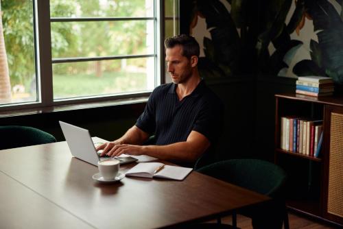 a man sitting at a table using a laptop computer at Uma House by Yurbban South Beach in Miami Beach