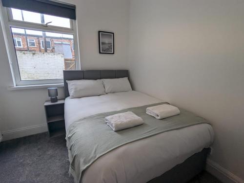 a bedroom with a bed with two towels on it at AA Exec Apartments in South Shields