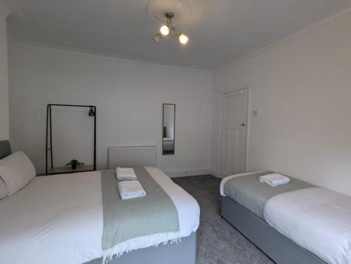 a bedroom with two beds and a mirror at AA Exec Apartments in South Shields