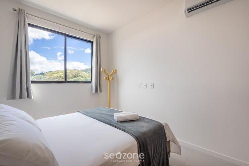 a white bedroom with a bed and a window at Apto c/ Churrasqueira a 750 m da Praia RRV0202 in Gravata