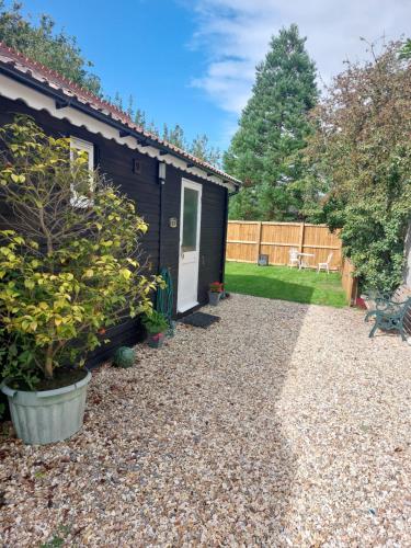 a garden with a small shed and a gravel driveway at The Garden Room at Poplar Cottage - Weston-super-Mare in Wick Saint Lawrence