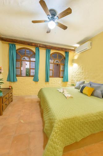 a bedroom with a green bed and a ceiling fan at Zihua 6bed 3bath Home for 12 with Direct Access to Beach in Zihuatanejo