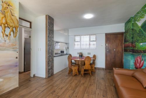 a living room with a dining room table and a kitchen at Beach Front Self Catering Apartment With Pool in Durban