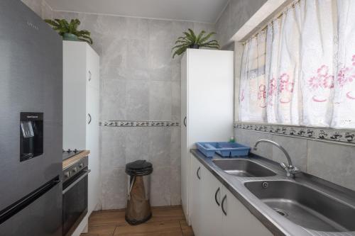 a small kitchen with a sink and a window at Beach Front Self Catering Apartment With Pool in Durban