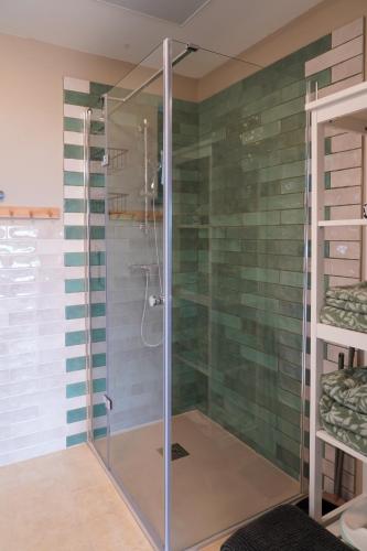 a glass shower in a bathroom with green tiles at Sümeg Horizon in Sümeg