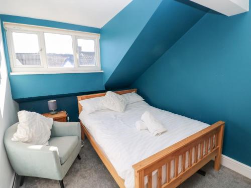 a blue bedroom with a bed and a chair at Castleview Coastal Comfort in Oystermouth
