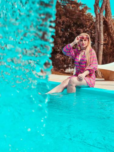 a woman sitting on the edge of a swimming pool at DM Thermas Hotel Irai in Iraí
