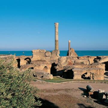 an old stone building with a chimney next to the ocean at Dar kmar in Tunis
