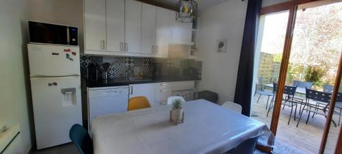 a kitchen with a table and a white refrigerator at Un Havre de Calme - proche Ferme de la Doudou in Cheptainville