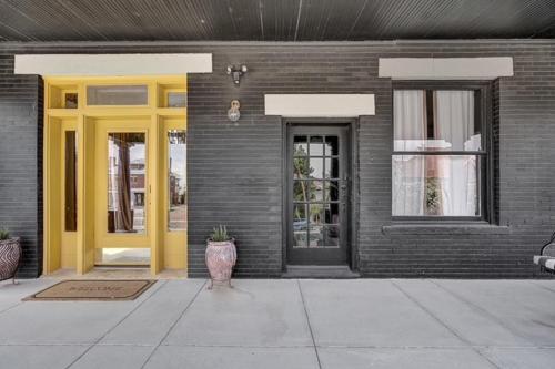 a brick building with yellow doors and a porch at Cozy Casa Mina 1br Near Downtown Parking in El Paso