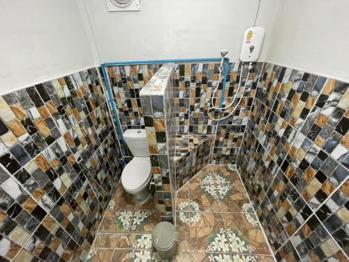 een badkamer met een toilet en een mozaïektegels muur bij โฮมสเตย์ติดแม่น้ำปิง in Sam Ngao