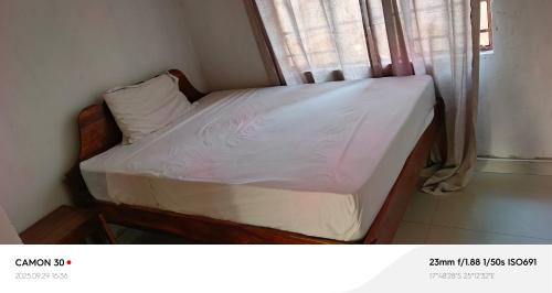 a small bed in a room with a window at Benly's Nest in Kasane