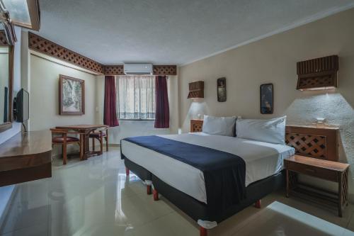 a hotel room with a bed and a desk and a table at Hotel Plaza Kokai Cancún in Cancún