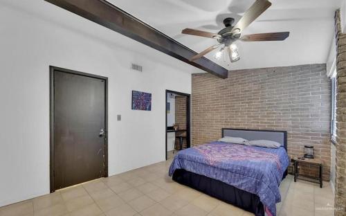 a bedroom with a ceiling fan and a brick wall at Charming 1BR Condo Near UTRGV & Downtown Edinburg in Edinburg