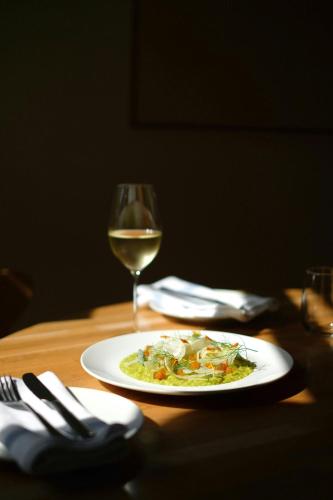 a plate of food and a glass of wine on a table at Domes Miramare, a Luxury Collection Resort, Corfu - Adults Only in Moraitika