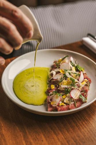 a plate of food with a spoonful of mustard at Domes Miramare, a Luxury Collection Resort, Corfu - Adults Only in Moraitika