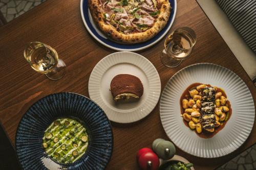 a table with plates of food and a pizza at Domes Miramare, a Luxury Collection Resort, Corfu - Adults Only in Moraitika