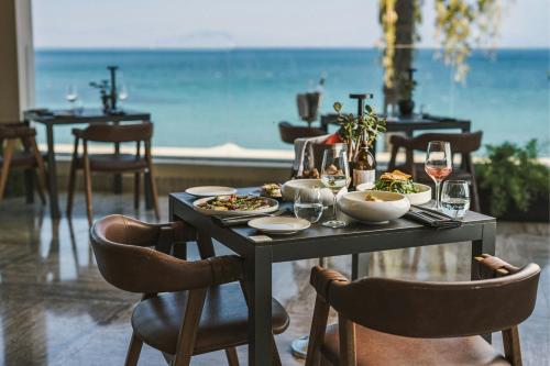 a table with plates of food and glasses of wine at Domes Miramare, a Luxury Collection Resort, Corfu - Adults Only in Moraitika