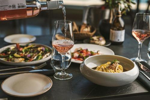 a table with a bowl of pasta and a glass of wine at Domes Miramare, a Luxury Collection Resort, Corfu - Adults Only in Moraitika